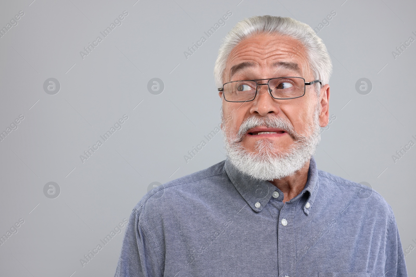 Photo of Portrait of embarrassed senior man on light grey background, space for text