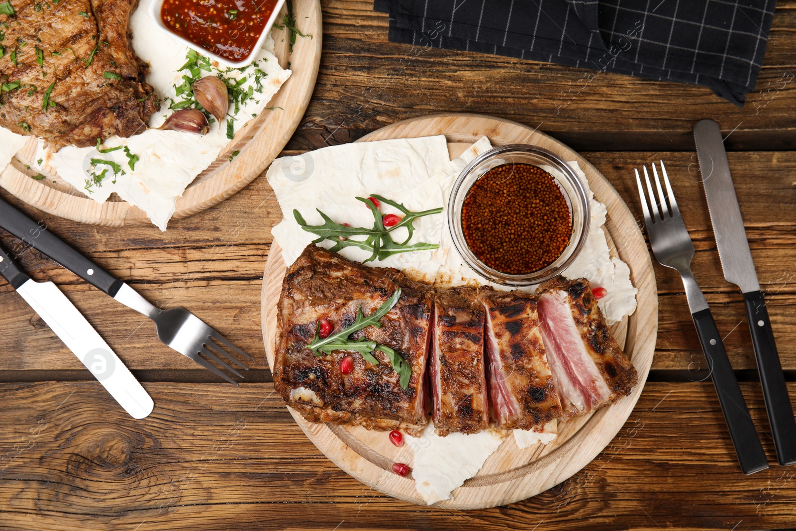 Photo of Delicious grilled ribs served on wooden table, flat lay