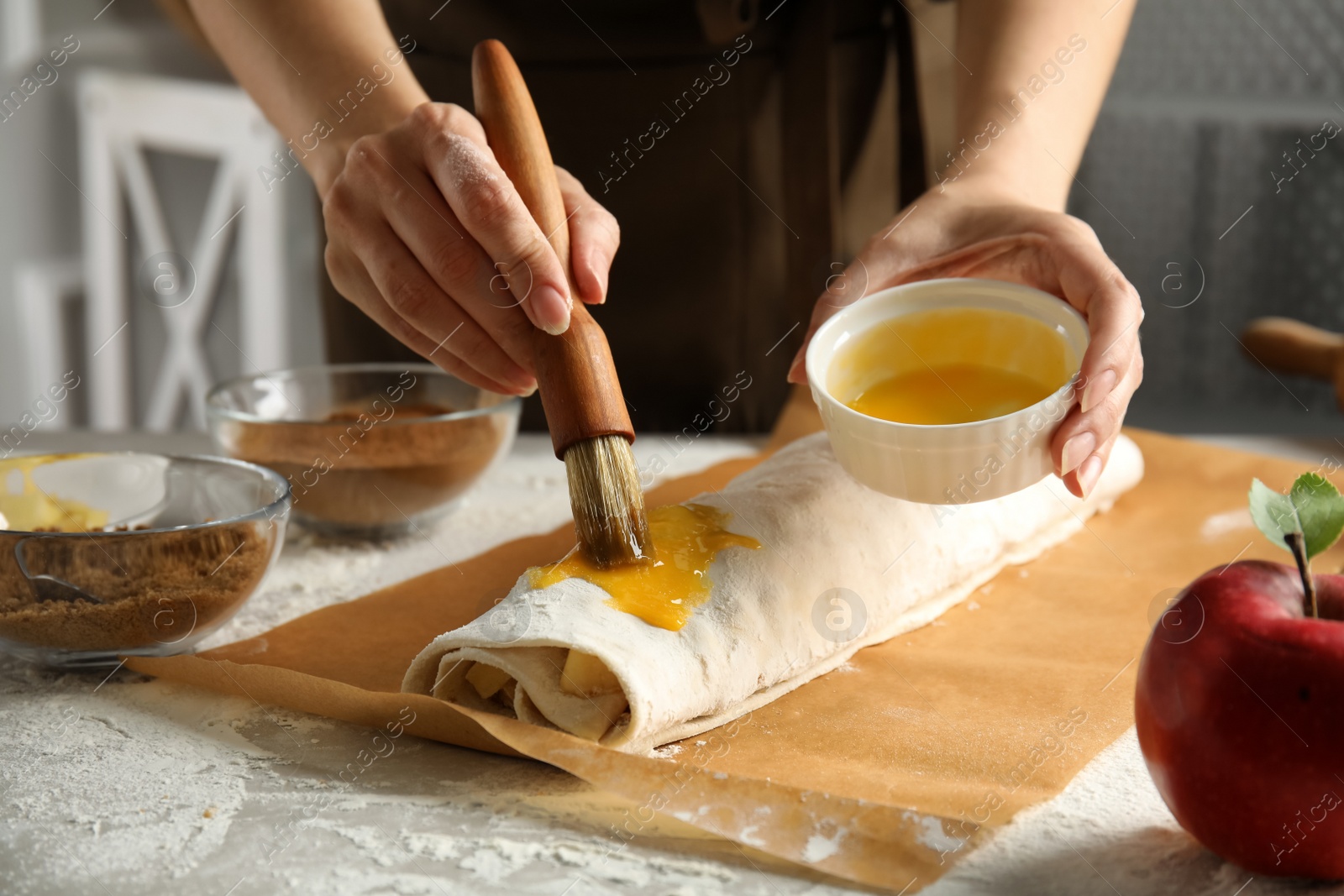 Photo of Woman making delicious apple strudel at table, closeup