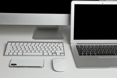 Photo of Computer monitor, laptop with mouse and smartphone on table