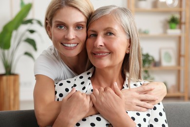 Happy mature mother and her daughter hugging at home