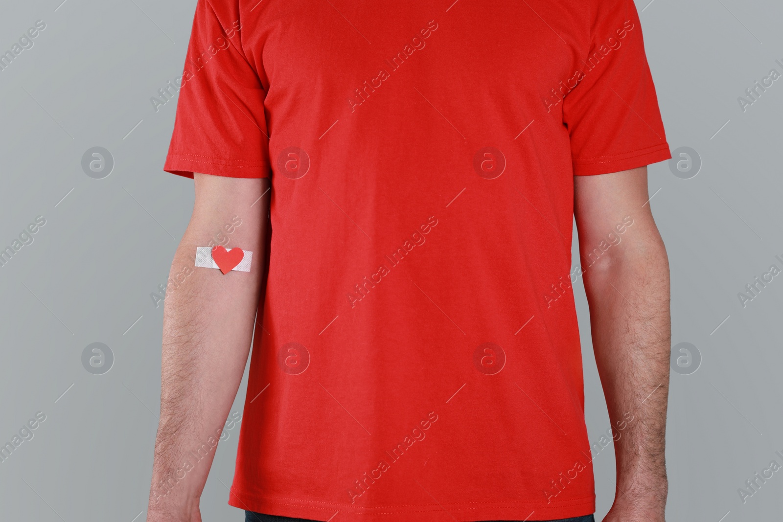 Photo of Blood donation concept. Man with adhesive plaster on arm against grey background, closeup