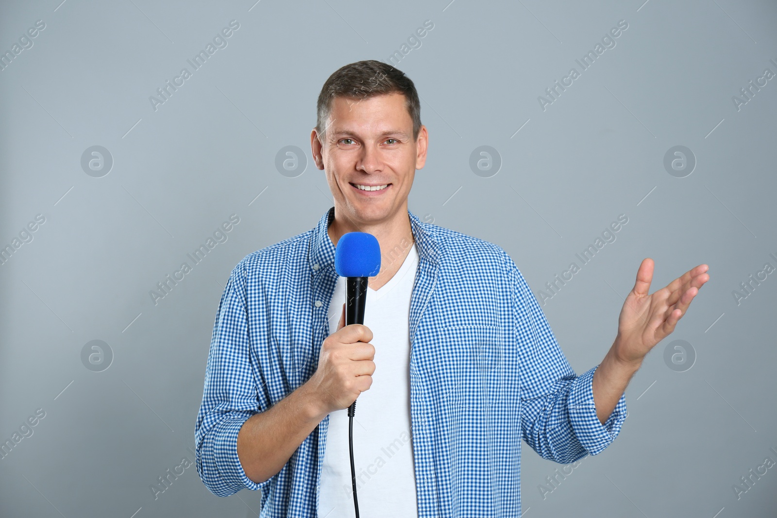 Photo of Male journalist with microphone on grey background