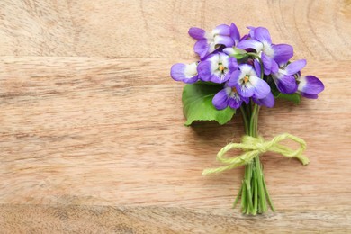Photo of Beautiful wild violets and space for text on wooden table, top view. Spring flowers