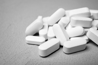 Photo of White pills on grey background, closeup