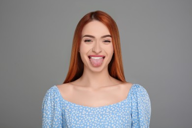 Photo of Happy woman showing her tongue on gray background