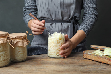 Photo of Woman with fermented cabbage at wooden table, closeup