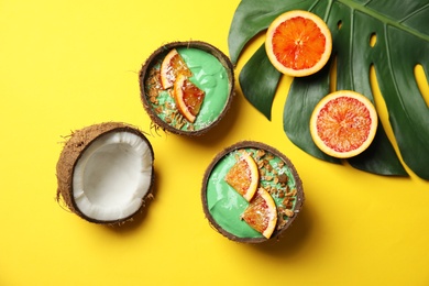 Coconut shells with yummy spirulina smoothie on color background, top view