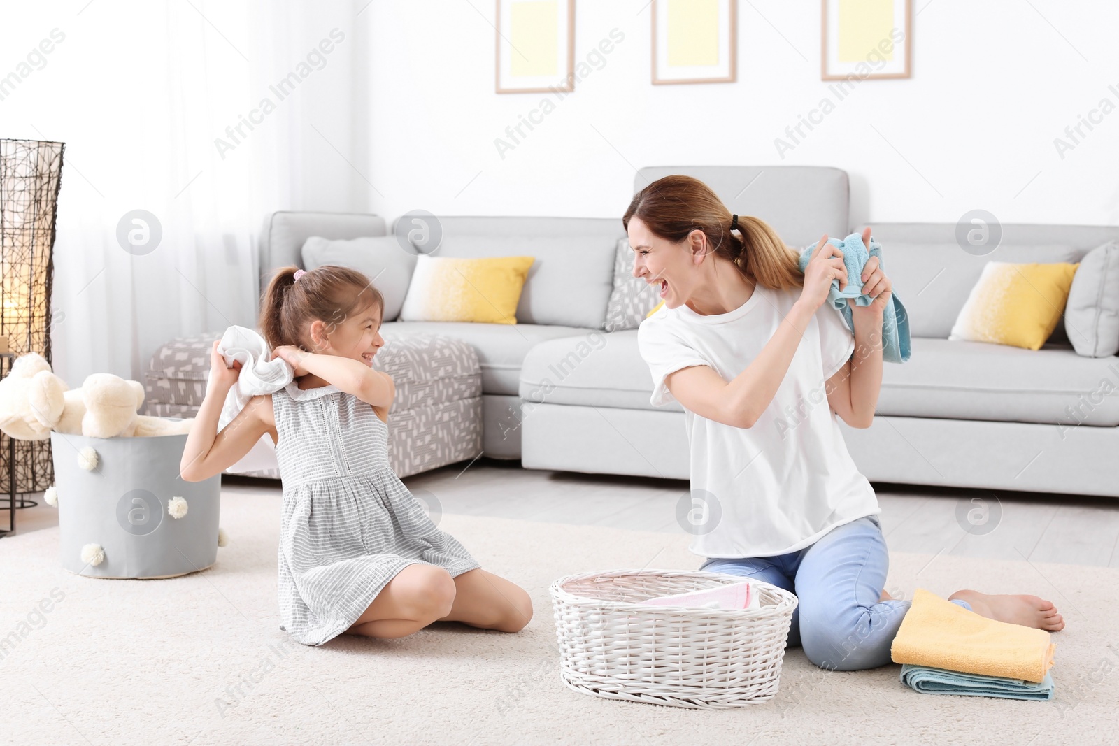 Photo of Housewife and daughter having fun while folding freshly washed towels in room