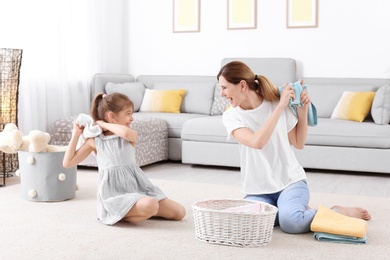 Housewife and daughter having fun while folding freshly washed towels in room