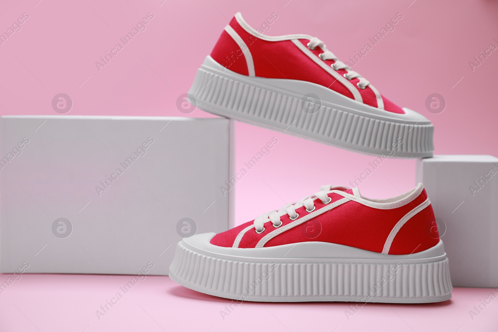 Photo of Stylish presentation of red classic old school sneakers on pink background