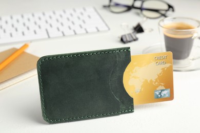 Leather card holder with credit card, stationery, coffee and keyboard on white table