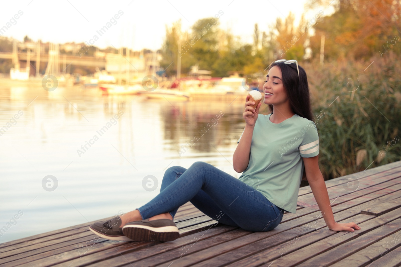 Photo of Happy young woman with delicious ice cream in waffle cone outdoors. Space for text
