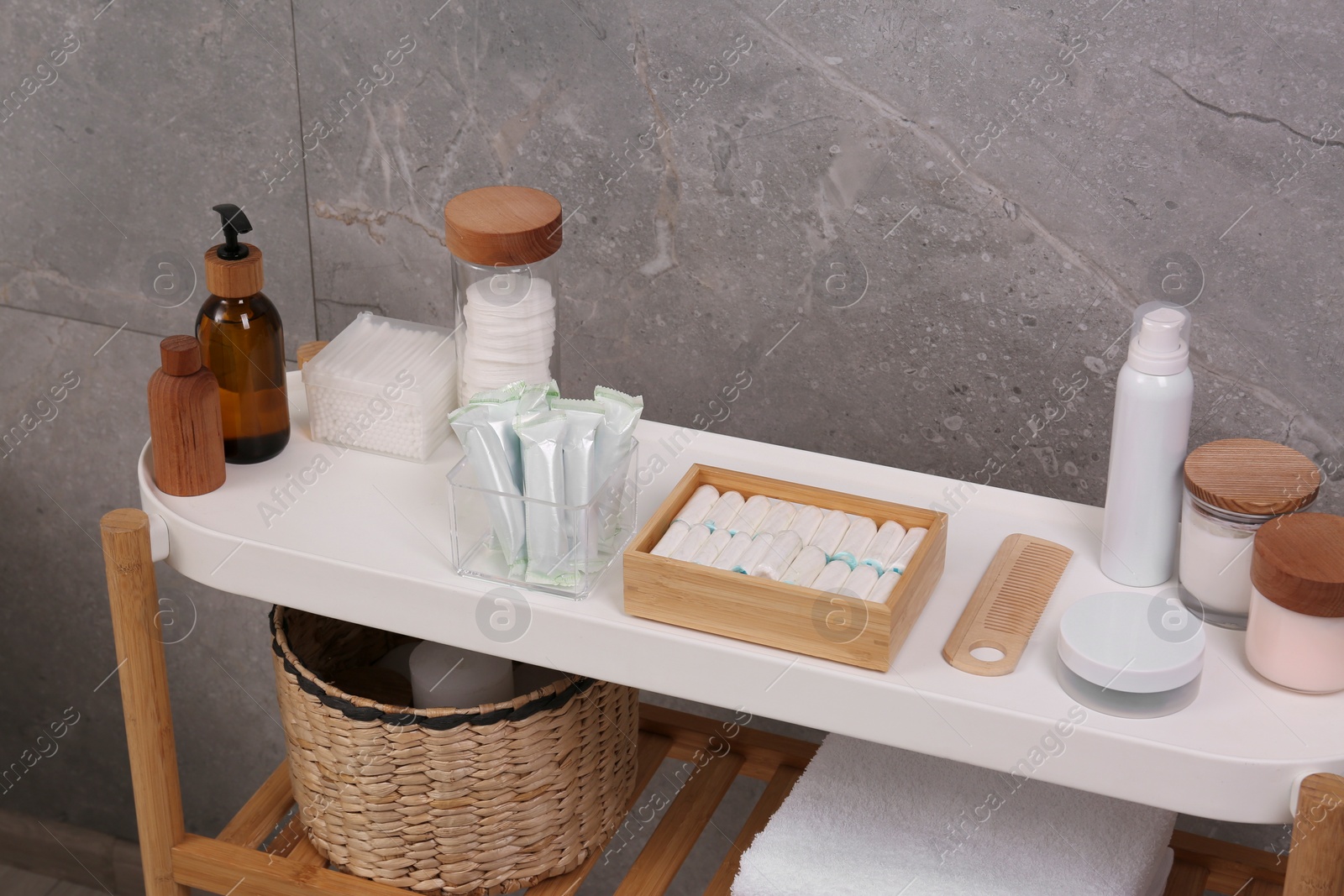 Photo of Many different tampons and personal care products on white table near grey wall