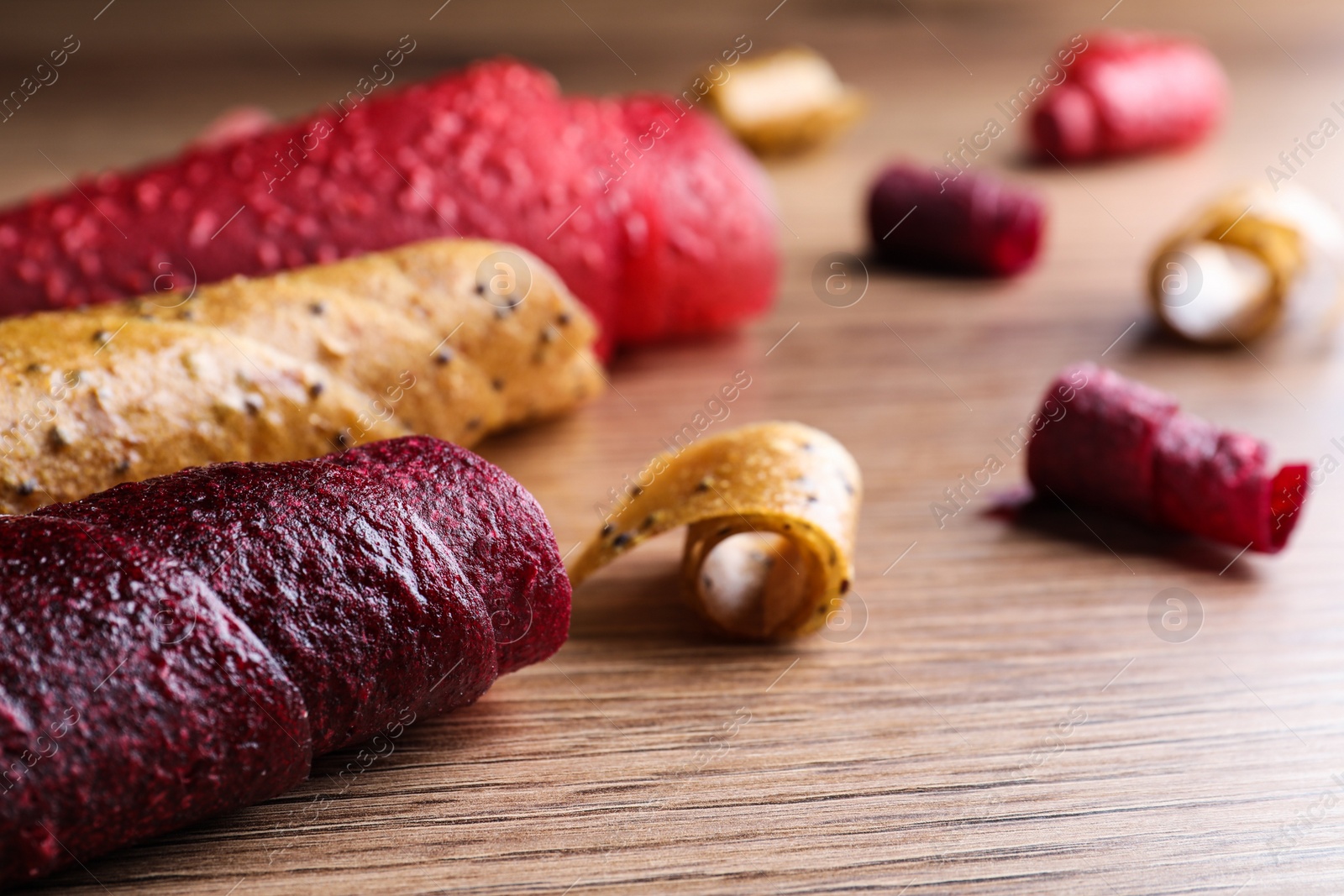 Photo of Delicious fruit leather rolls on wooden table, closeup