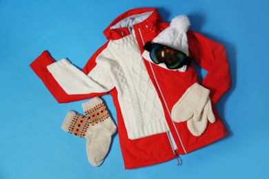 Photo of Stylish winter sport clothes on light blue background, flat lay