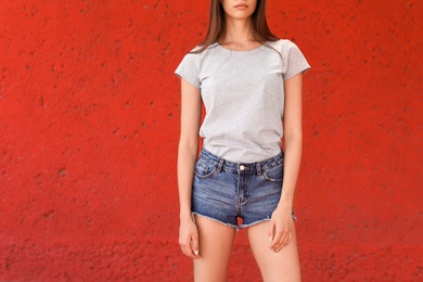 Photo of Young woman wearing gray t-shirt near color wall on street