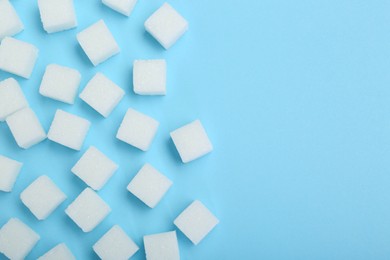 Photo of White sugar cubes on light blue background, top view. Space for text