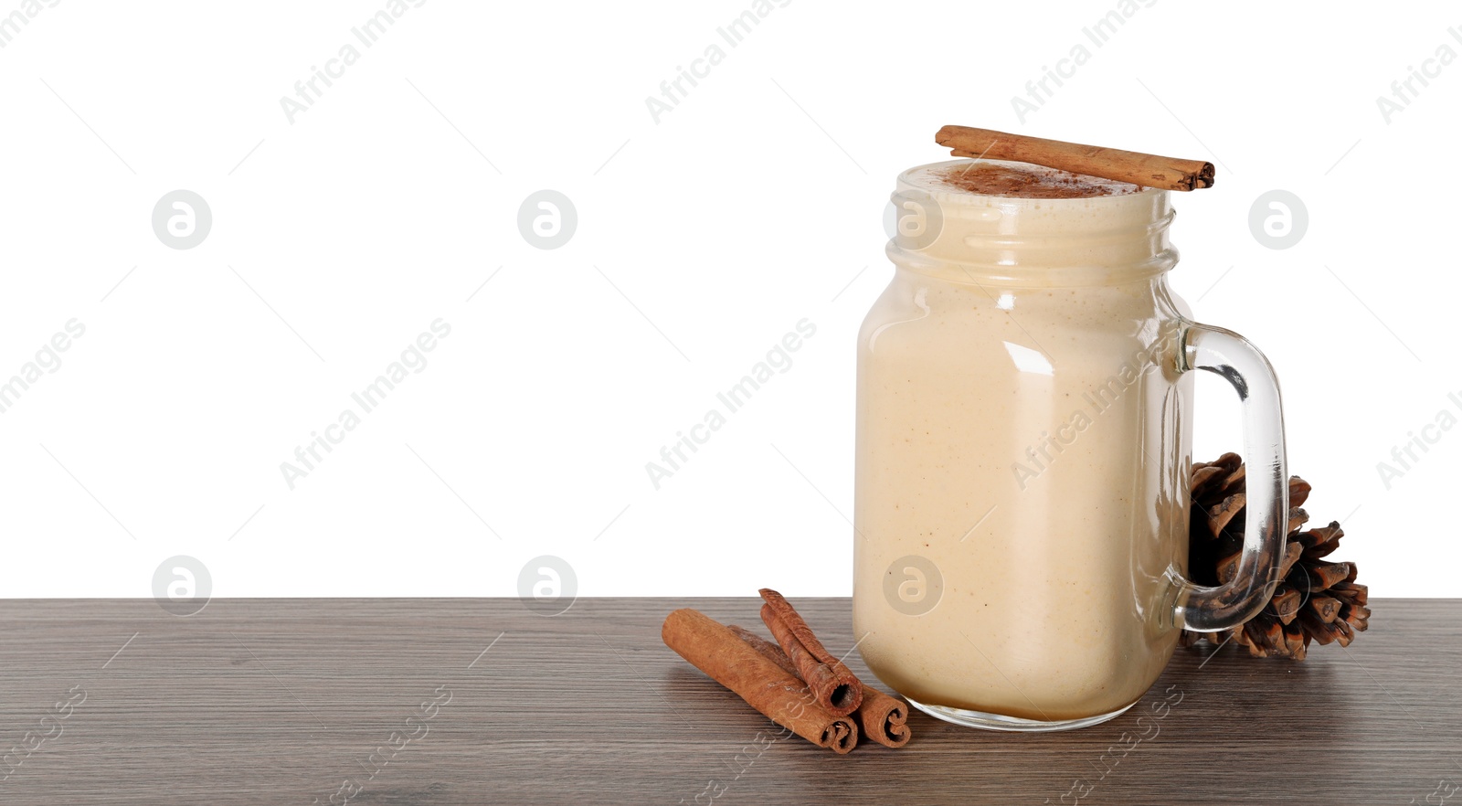 Photo of Delicious eggnog and cinnamon sticks on wooden table against white background. Space for text