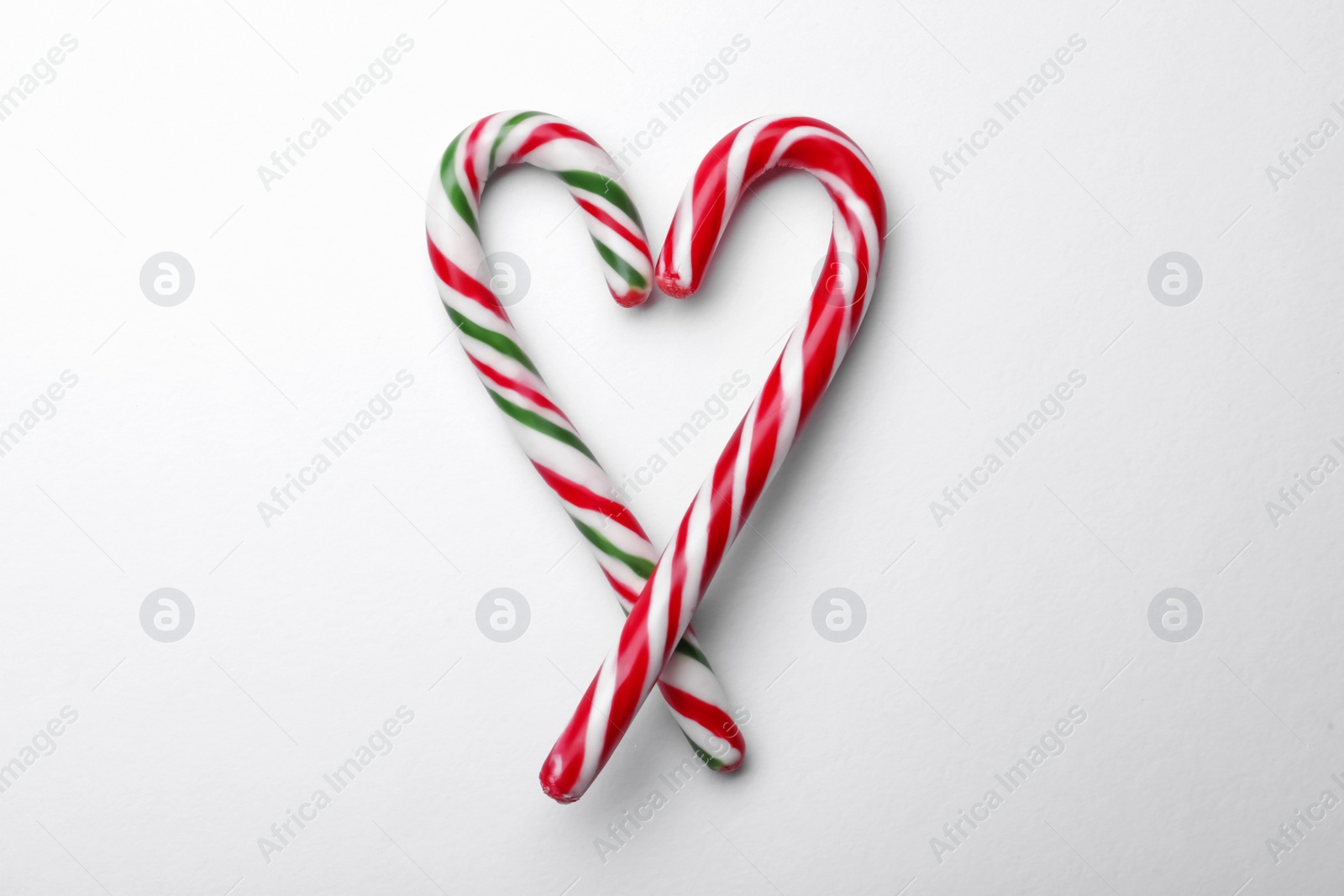 Photo of Heart made of sweet Christmas candy canes on white background, top view