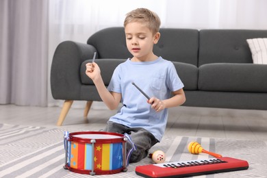 Photo of Little boy playing toy drum at home