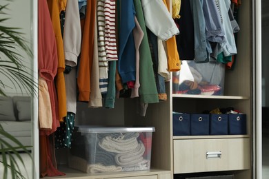 Wardrobe closet with different stylish clothes and home stuff in room. Fast fashion