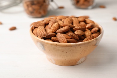 Photo of Tasty organic almond nuts in bowl on table