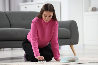 Woman with brush removing pet hair from carpet at home