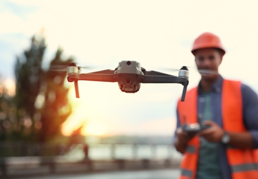 Builder operating drone with remote control at construction site, focus on quadcopter. Aerial survey