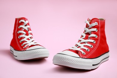 Photo of Pair of new stylish red sneakers on pink background