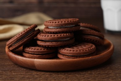 Tasty chocolate sandwich cookies with cream on wooden table, closeup