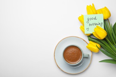 Photo of Cup of aromatic coffee, beautiful yellow tulips and Good Morning note on white background, flat lay. Space for text