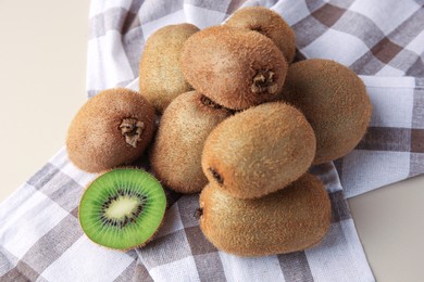 Photo of Heap of whole and cut fresh kiwis on beige table, above view
