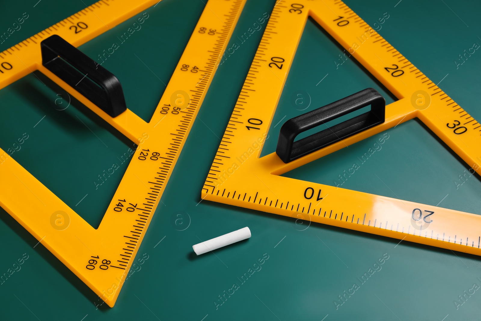 Photo of Yellow triangles and chalk on green chalkboard, closeup