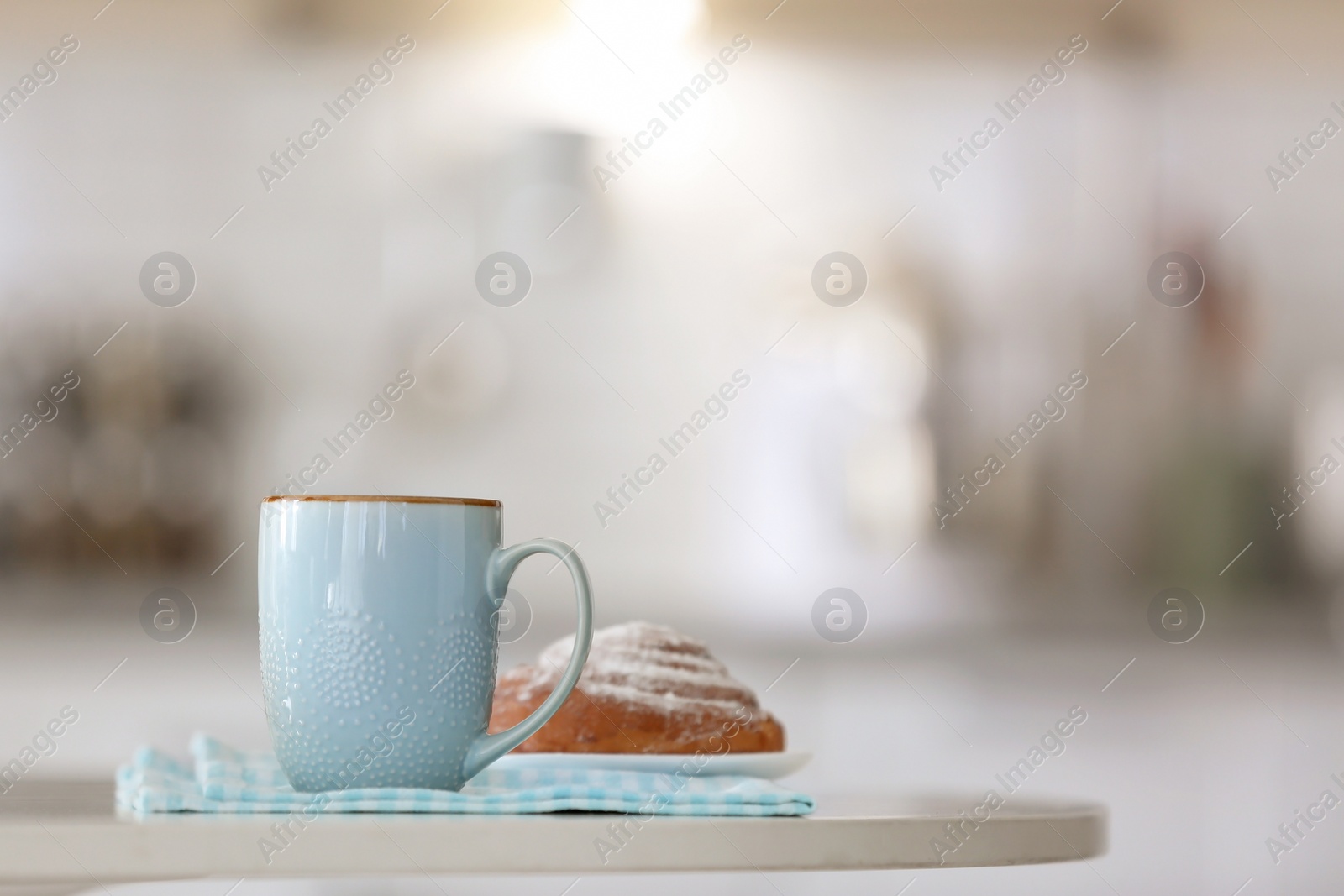 Photo of Cup of coffee and tasty bun on table