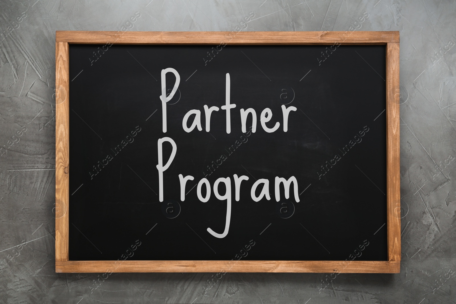 Image of Black chalkboard with words Partner Program on grey wall