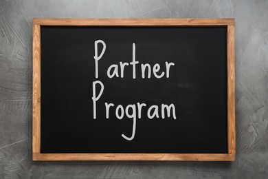 Image of Black chalkboard with words Partner Program on grey wall