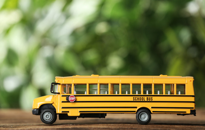 Yellow school bus on table against blurred background. Transport service