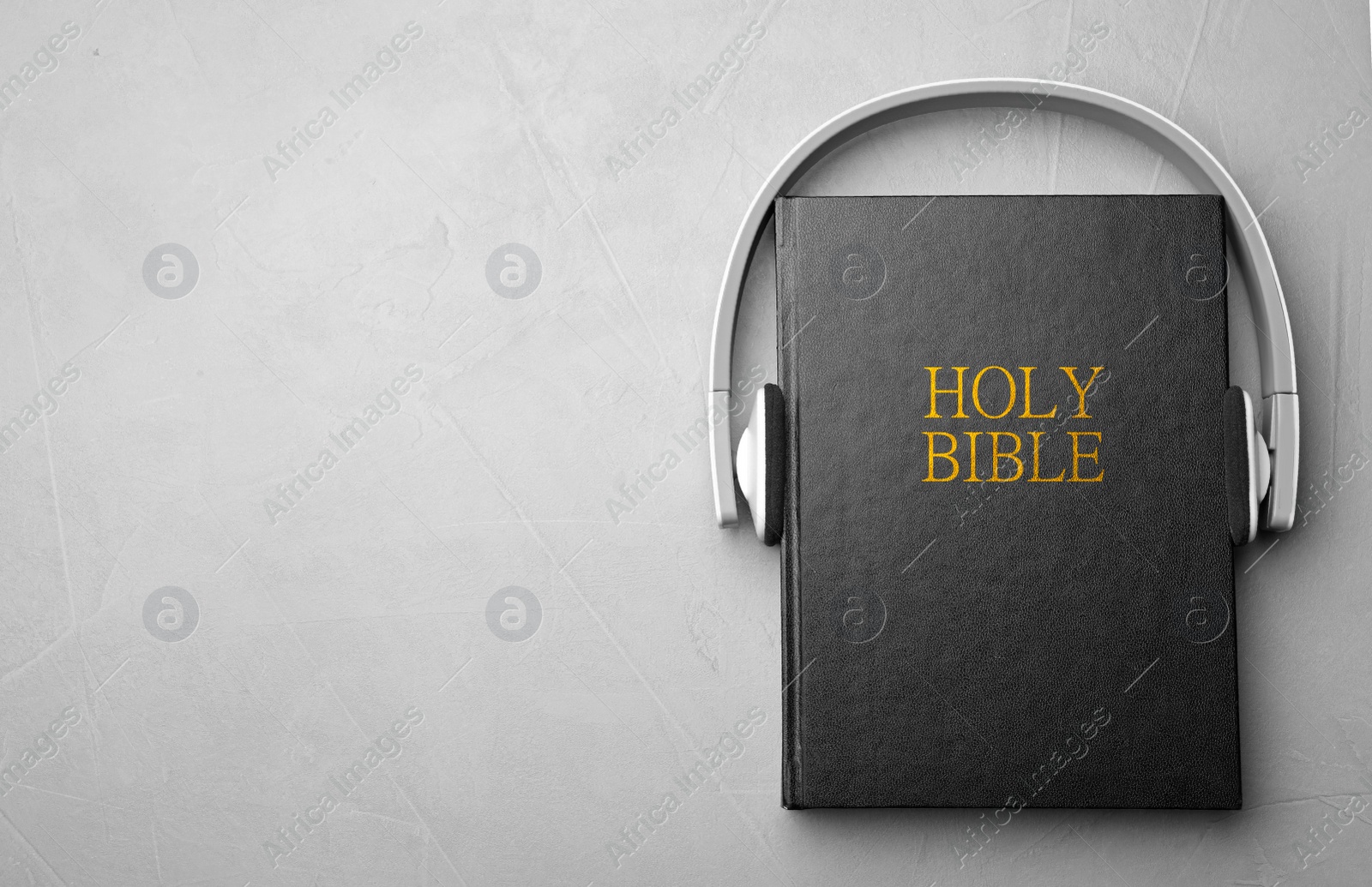 Photo of Bible and headphones on light grey background, top view with space for text. Religious audiobook