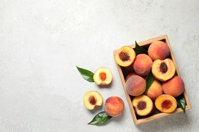 Photo of Delicious juicy peaches and leaves on light grey textured table, flat lay. Space for text