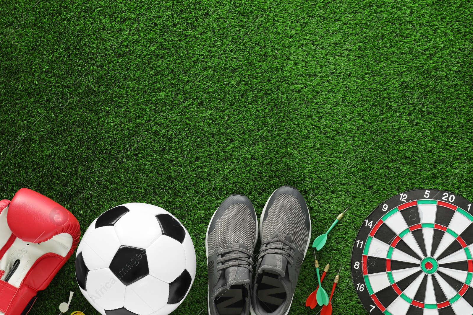 Photo of Different sport equipment and sneakers on green grass, flat lay. Space for text