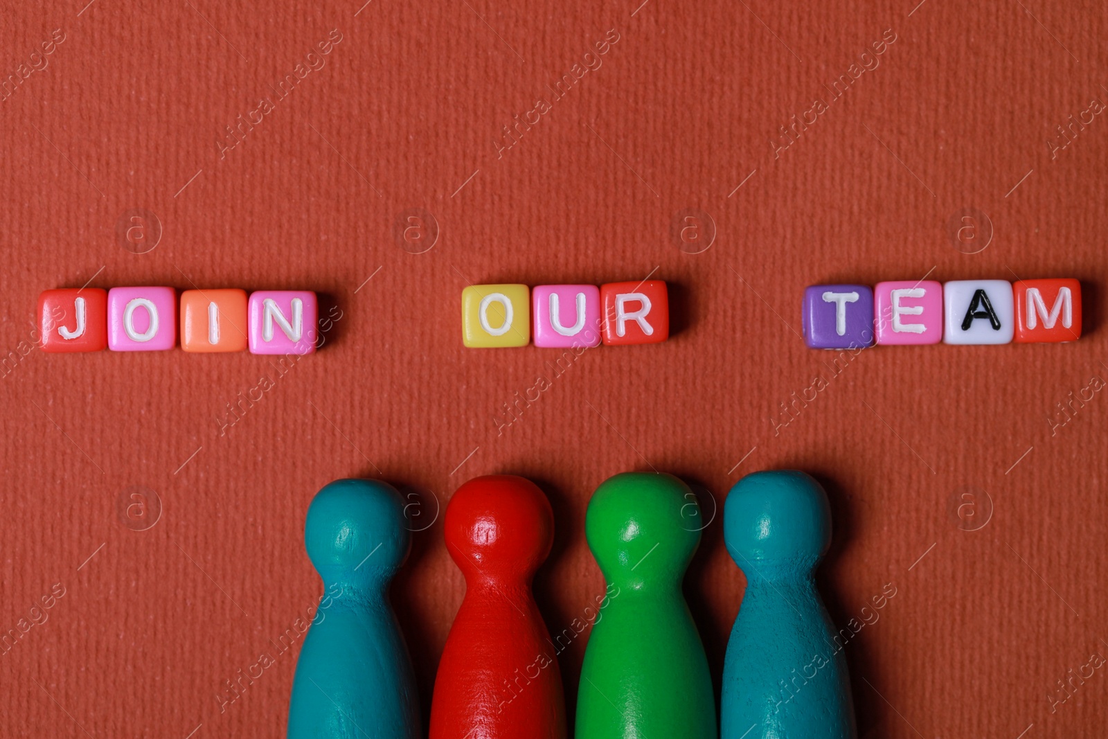 Photo of Colorful cubes with phrase Join Our Team and pawns on red background, flat lay. Recruiter searching employee