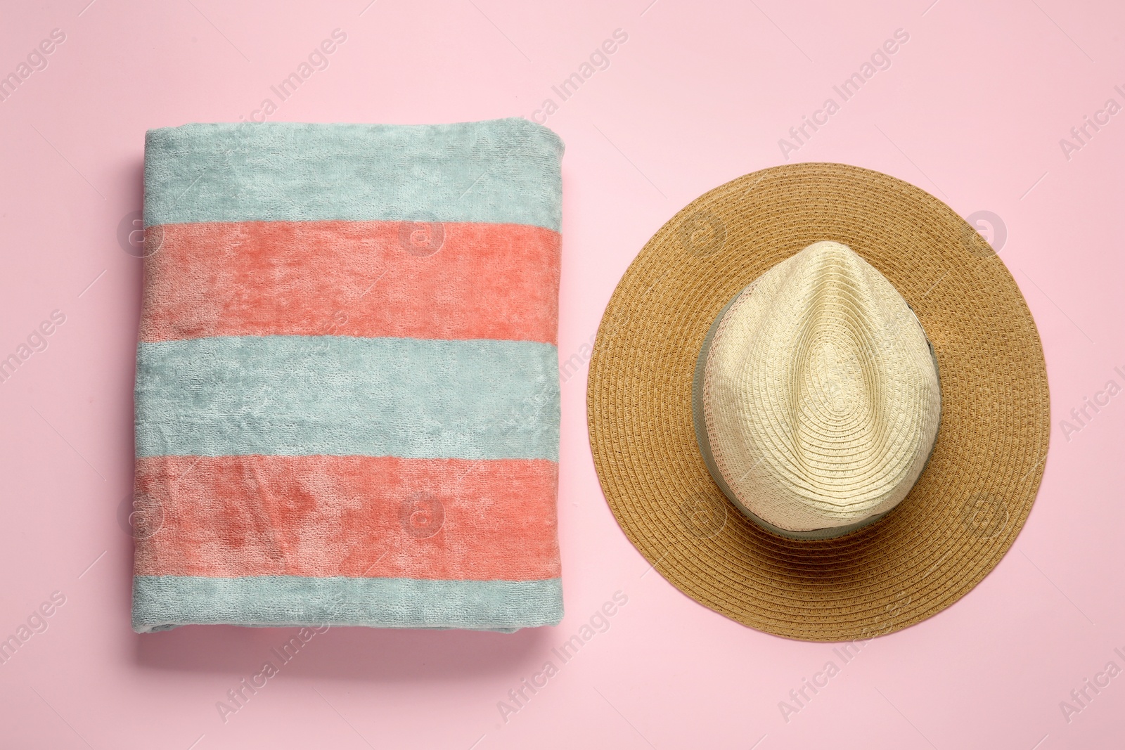 Photo of Beach towel and hat on pink background, flat lay