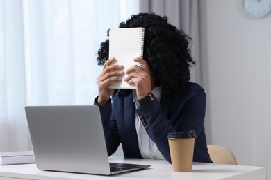 Photo of Deadline concept. Woman covering face with notepad in office