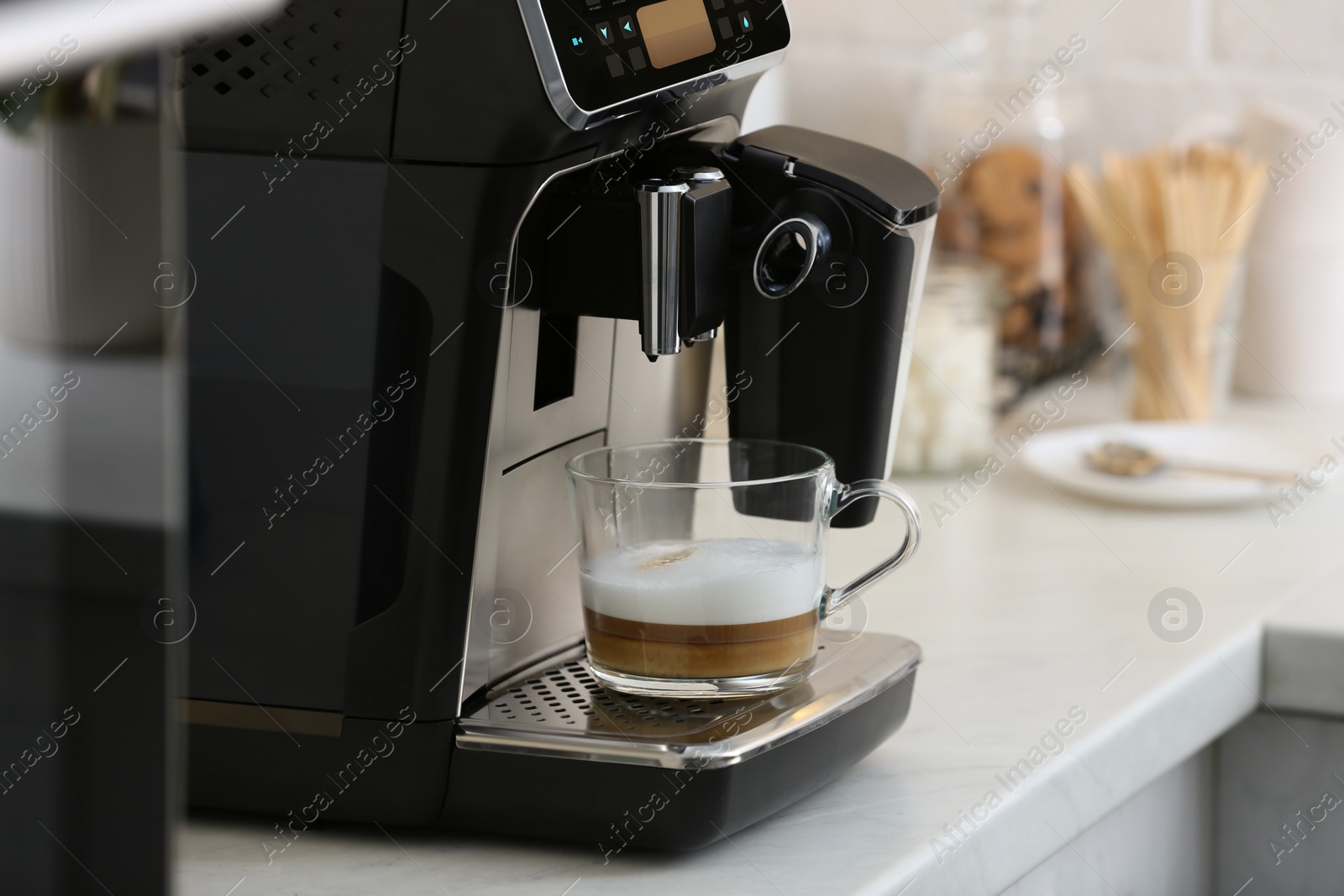 Photo of Modern espresso machine and glass cup of coffee on white marble countertop in kitchen