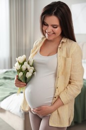 Photo of Young pregnant woman with flowers at home