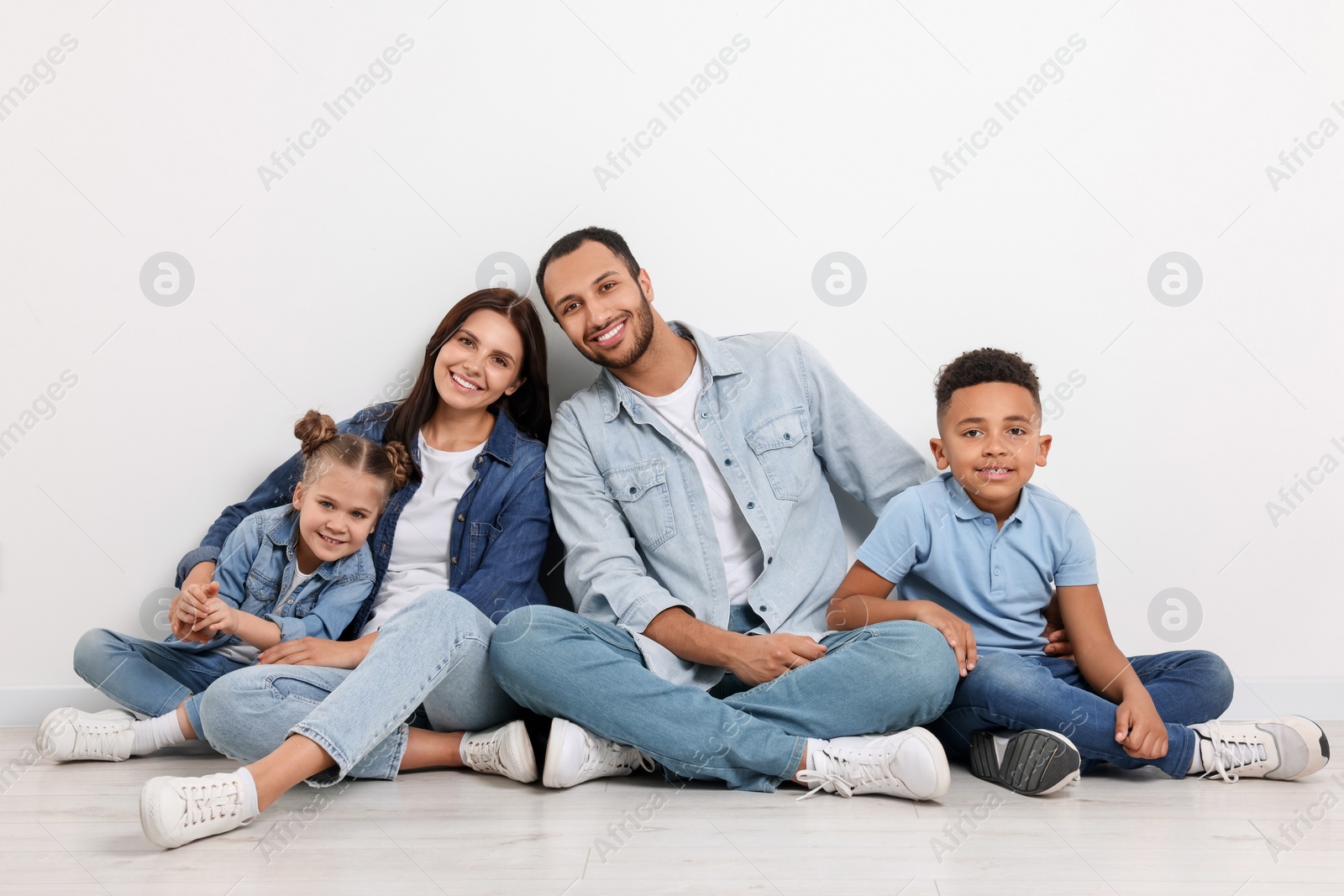 Photo of Happy international family sitting near white wall