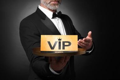 Photo of Man holding tray with VIP sign on black background, closeup