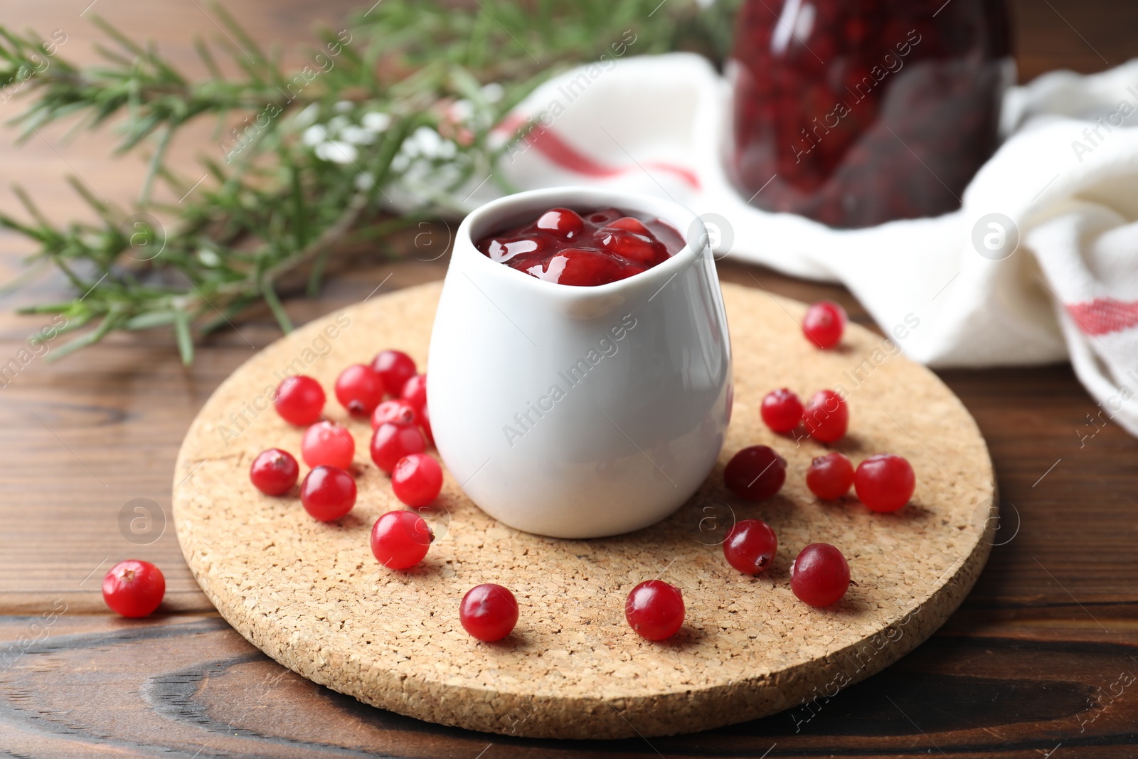 Photo of Cranberry sauce in pitcher and fresh berries on wooden table