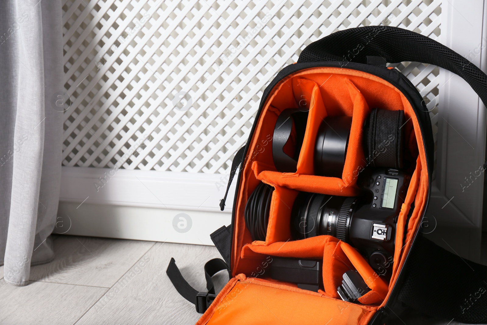 Photo of Bag with digital camera on floor indoors. Professional photographer's equipment
